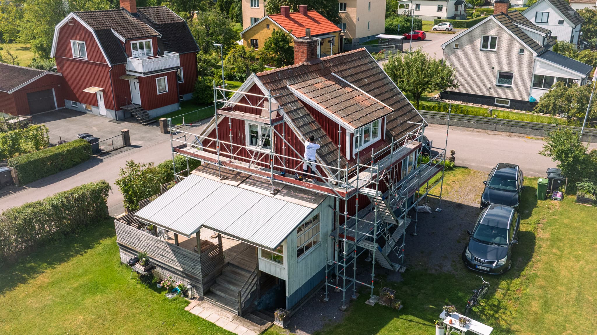 Fasadmålning av rött trähus med byggnadsställning i centrala Motala – Lundqvist Måleri & Fasad